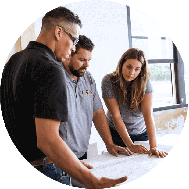 Building team discusses plans while reviewing blueprints on a job site.